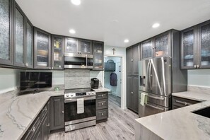 Una cocina moderna con armarios oscuros, una isla central con horno, refrigerador y microondas.