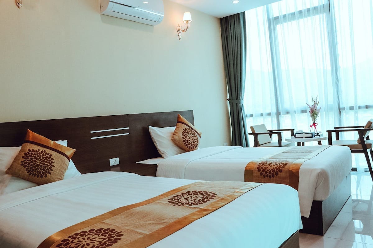 A hotel room with two beds, a desk, and a chair.
