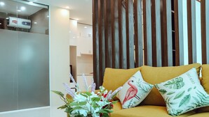 A modern living room with a sofa, decorative pillows, and a vase with flowers. - Nha hang & Khach San Tay Bac (Tuan Giao)