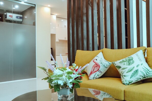 Una sala de estar moderna con un sofá, almohadones decorativos y un florero con flores.
