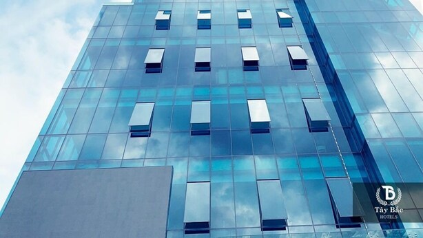 A modern high-rise building with a glass facade and multiple windows. - Nha hang & Khach San Tay Bac (Tuan Giao)