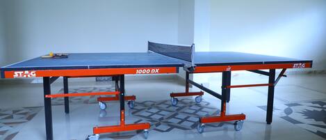 Una mesa de ping pong con ruedas, etiquetada "STAG 1000 BX", en una habitación con piso estampado.