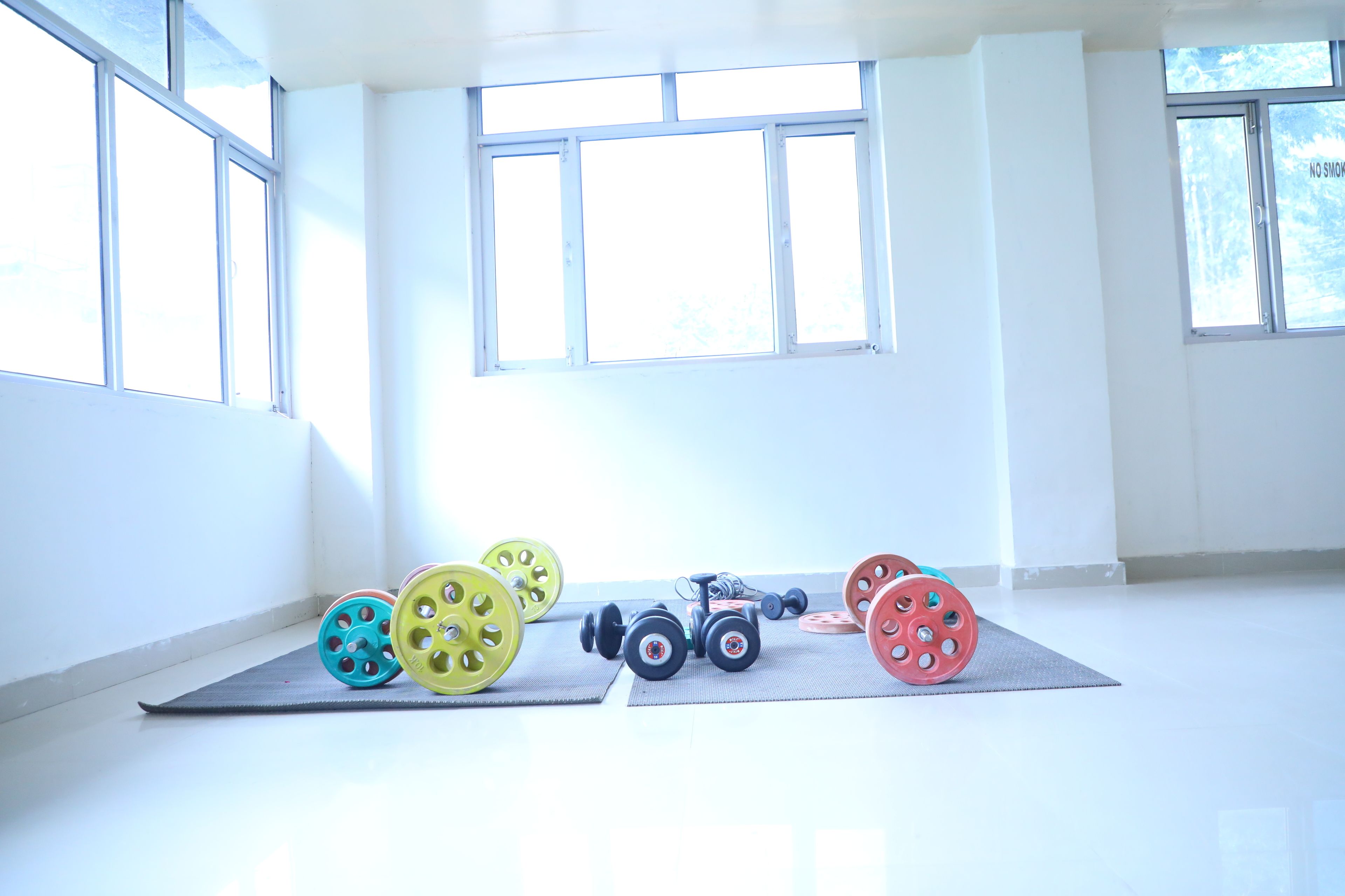 Una habitación luminosa con ventanas amplias, una colchoneta de yoga y pesas.