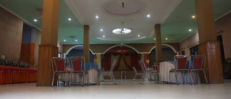 A spacious hall with high ceilings, multiple chandeliers, and rows of chairs.