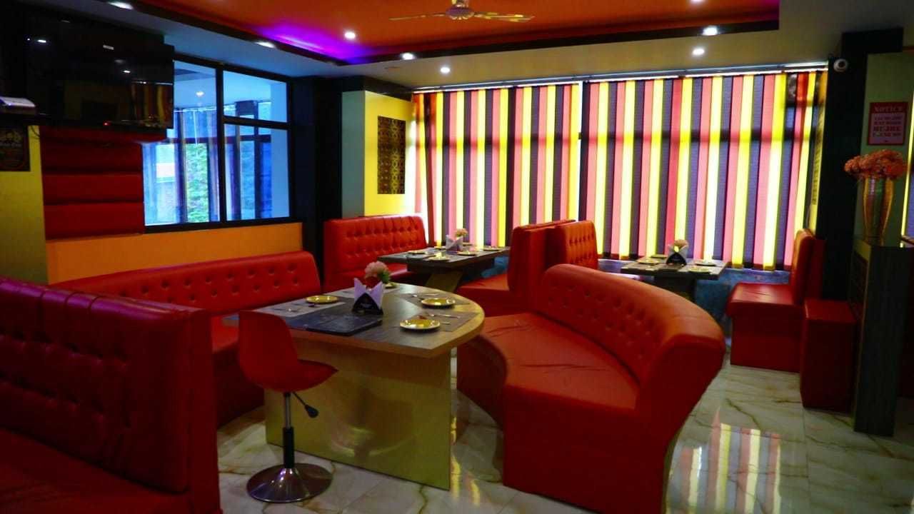 A restaurant with red upholstered booths, a central bar area, and a colorful striped wall.