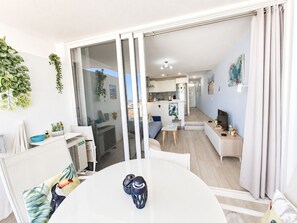 Un appartamento moderno con zona pranzo, cucina e soggiorno, con porte scorrevoli in vetro che si aprono su un balcone.