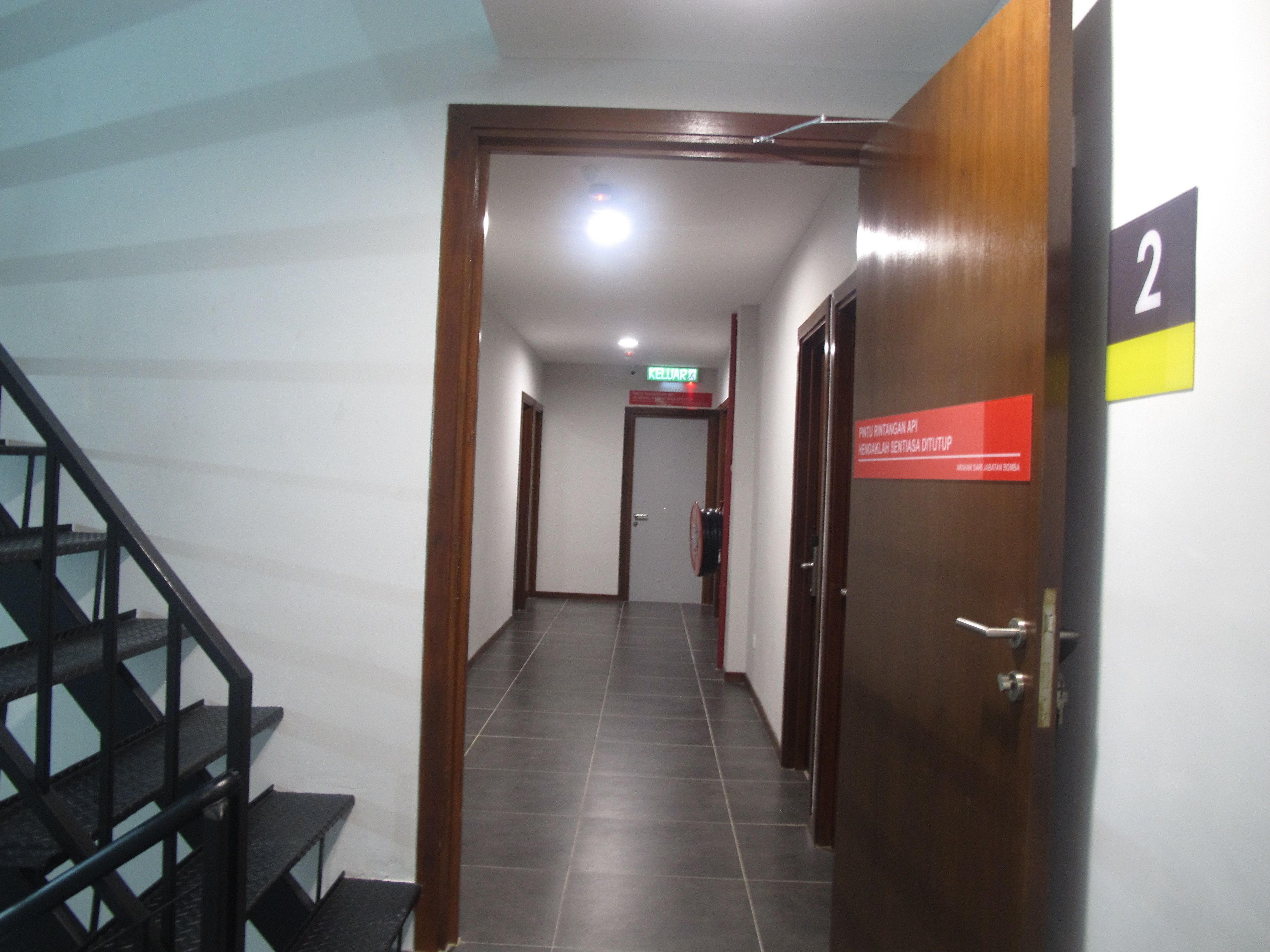 A hallway with a staircase on the left, a door labeled '2' on the right, and a sign above the door.