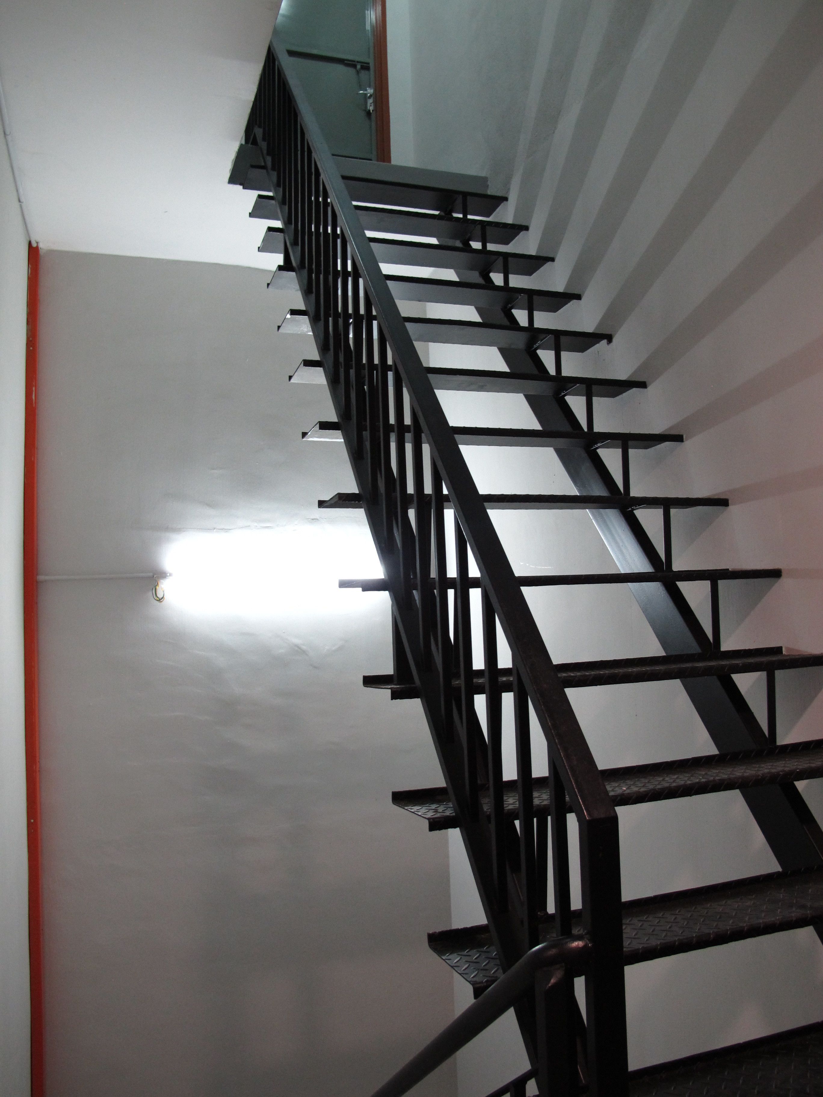 A staircase with a metal railing and a red trim at the base.