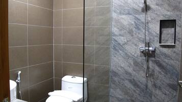A bathroom with a toilet, a shower, and a sink.