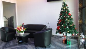 Una sala de estar moderna con un sofá de cuero negro, una mesita de centro y un árbol de Navidad decorado.