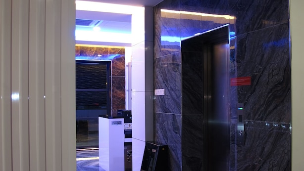 Un vestíbulo moderno con piso de mármol, una recepción y un quiosco digital de información.