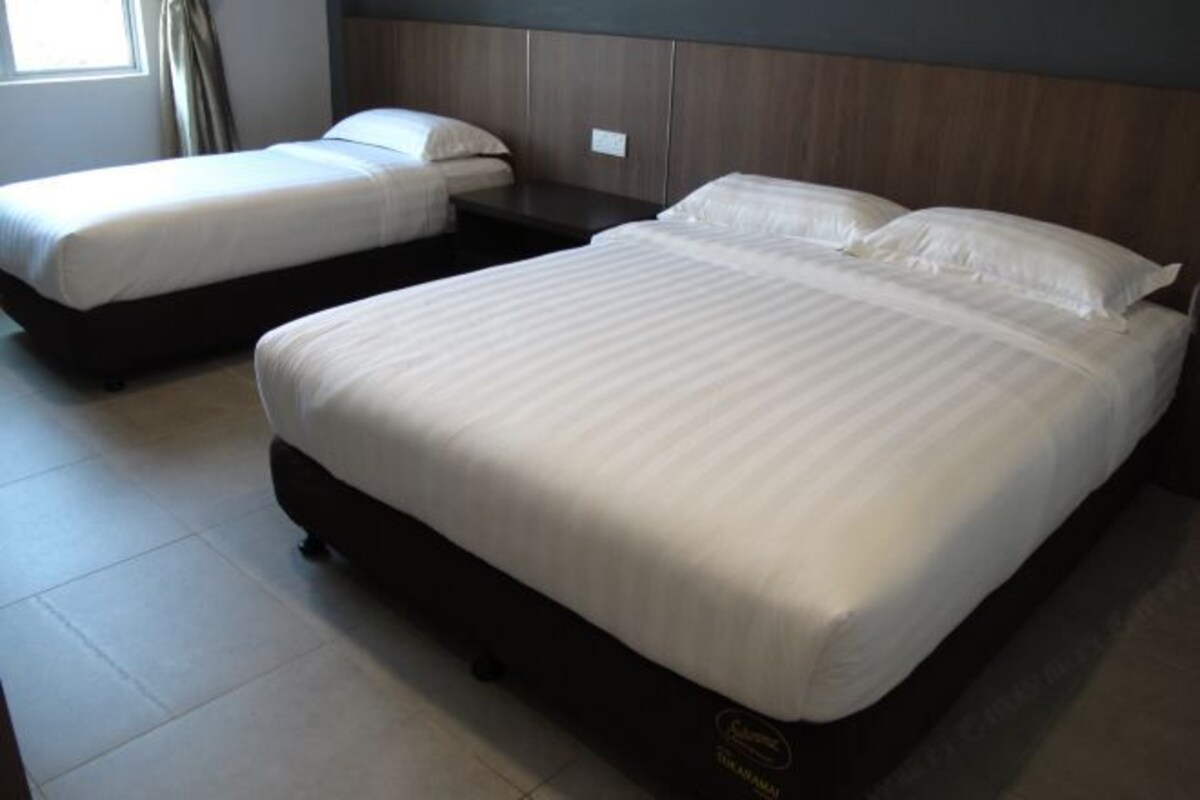 Una habitación de hotel con dos camas, un cabecero de madera y suelo de baldosas.