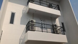 A multi-story building with balconies, air conditioning units, and a window on the left side. - Rumah Kayu Manis Tebet (Jakarta)