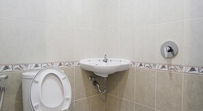 A bathroom with a toilet, sink, and a wall-mounted flush handle. - Rumah Kayu Manis Tebet (Jakarta)