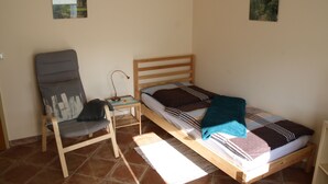 A small, simple room with a single bed, a chair, a nightstand, and two wall-mounted pictures. - Gästezimmer Lußhardthof (Sankt Leon-Rot)