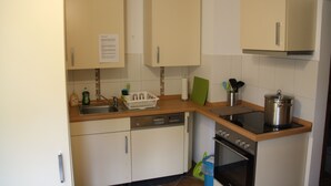 A kitchen with white cabinets, a dishwasher, an oven, and a stove. - Gästezimmer Lußhardthof (Sankt Leon-Rot)