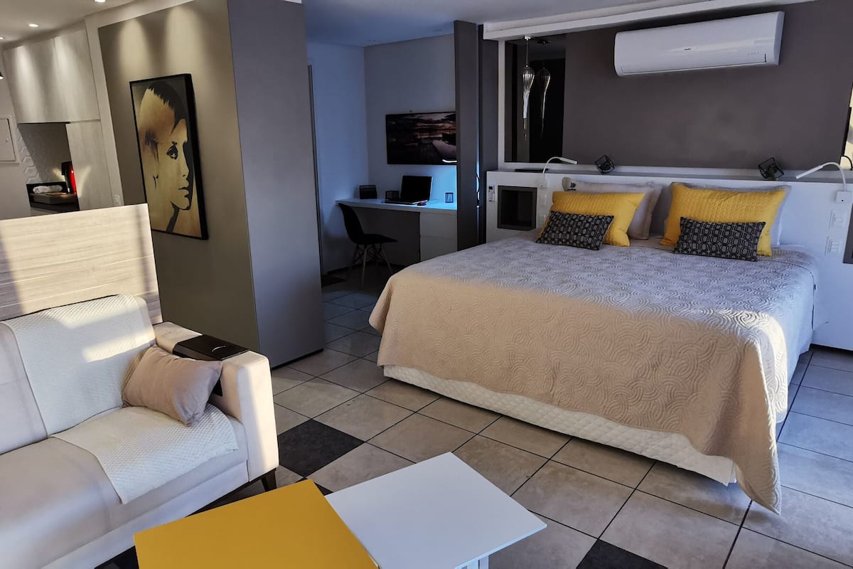 Una habitación de hotel moderna con cama, sofá, escritorio y una pequeña mesa.