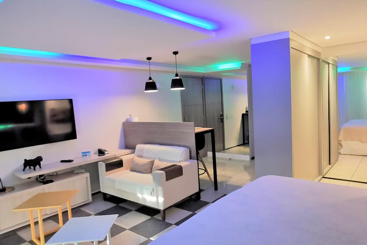 Una habitación de hotel moderna con una cama, un escritorio, una silla, un televisor y una mesita.