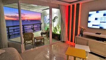 Una sala de estar moderna con balcón, televisión de pantalla plana y vistas al atardecer.
