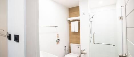 A modern bathroom with a bathtub, toilet, and shower.
