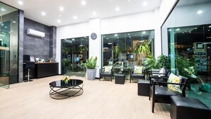 Un hall d’entrée moderne avec un comptoir d’accueil, un espace salon et de grandes fenêtres.