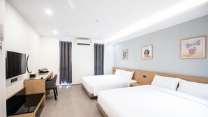 Une chambre d’hôtel avec deux lits, un bureau avec une chaise, une télévision et des œuvres d’art accrochées aux murs.