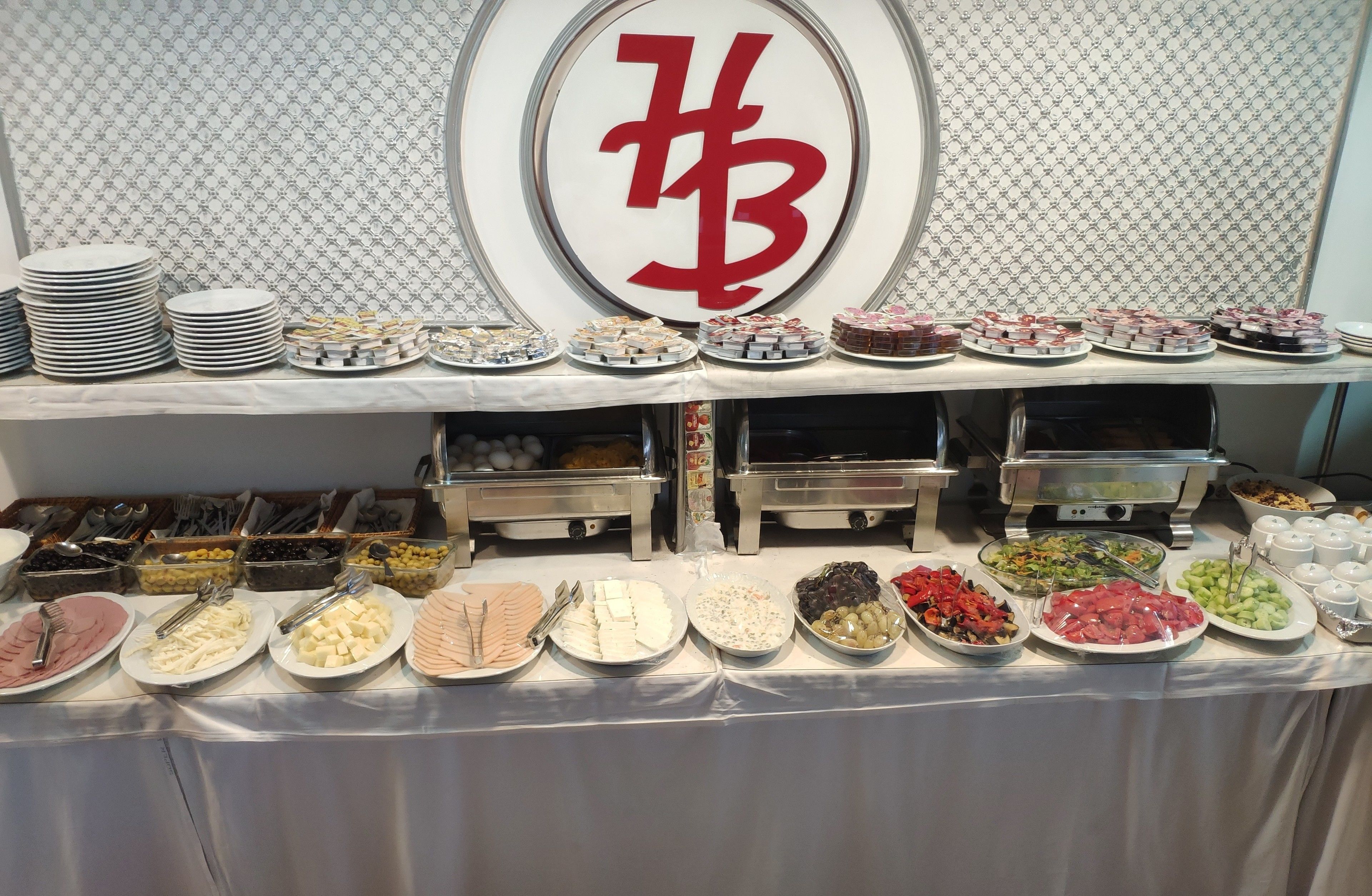 Une table de buffet garnie de divers aliments et d’ustensiles, notamment des assiettes, des bols et des récipients.