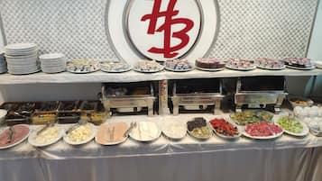 Une table de buffet garnie de divers aliments et d’ustensiles, notamment des assiettes, des bols et des récipients.