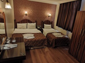 A hotel room with two beds, a wooden floor, a mirror, a bedside table with glasses and a tissue box, and a wall with patterned wallpaper. - Hotel Bazaar (Istanbul)