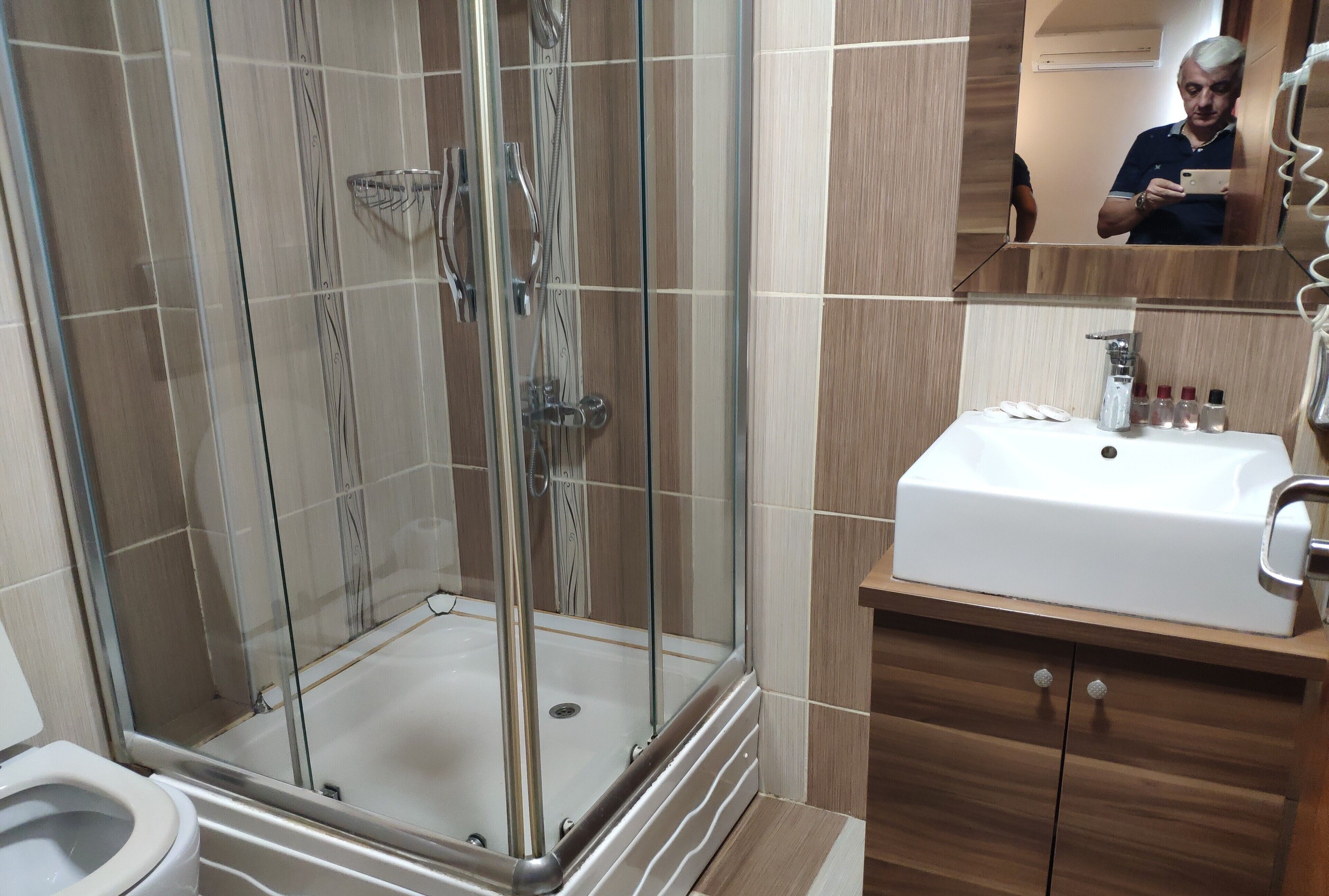 A modern bathroom with a glass-enclosed shower, a white sink, and wooden cabinetry.
