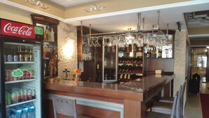Una zona de bar con un refrigerador de Coca-Cola, botellas de vino y copas.
