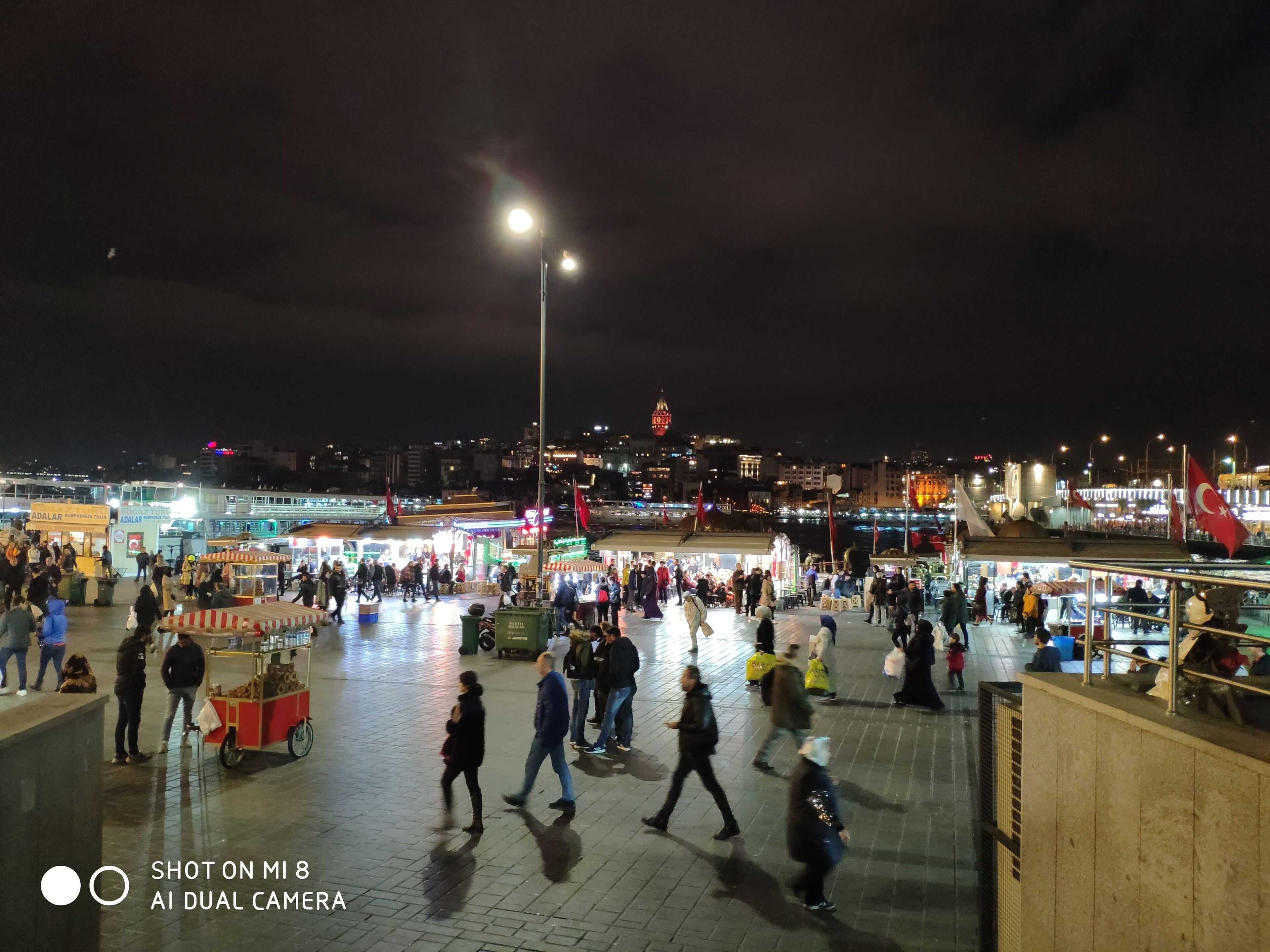 A bustling nighttime market with people walking and vendors selling goods.