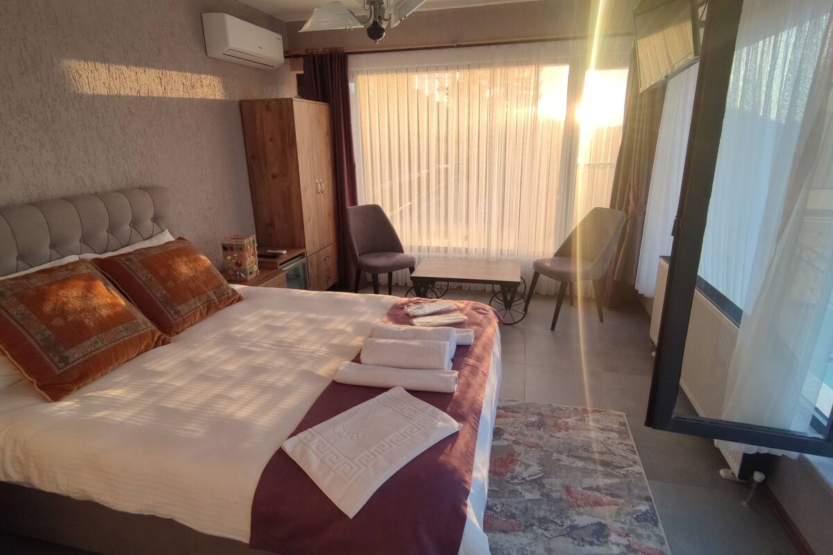 A hotel room with a bed, a desk, a chair, and a window with curtains.