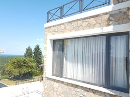 Un edificio moderno con fachada de piedra, ventanas grandes y un balcón con barandilla metálica.