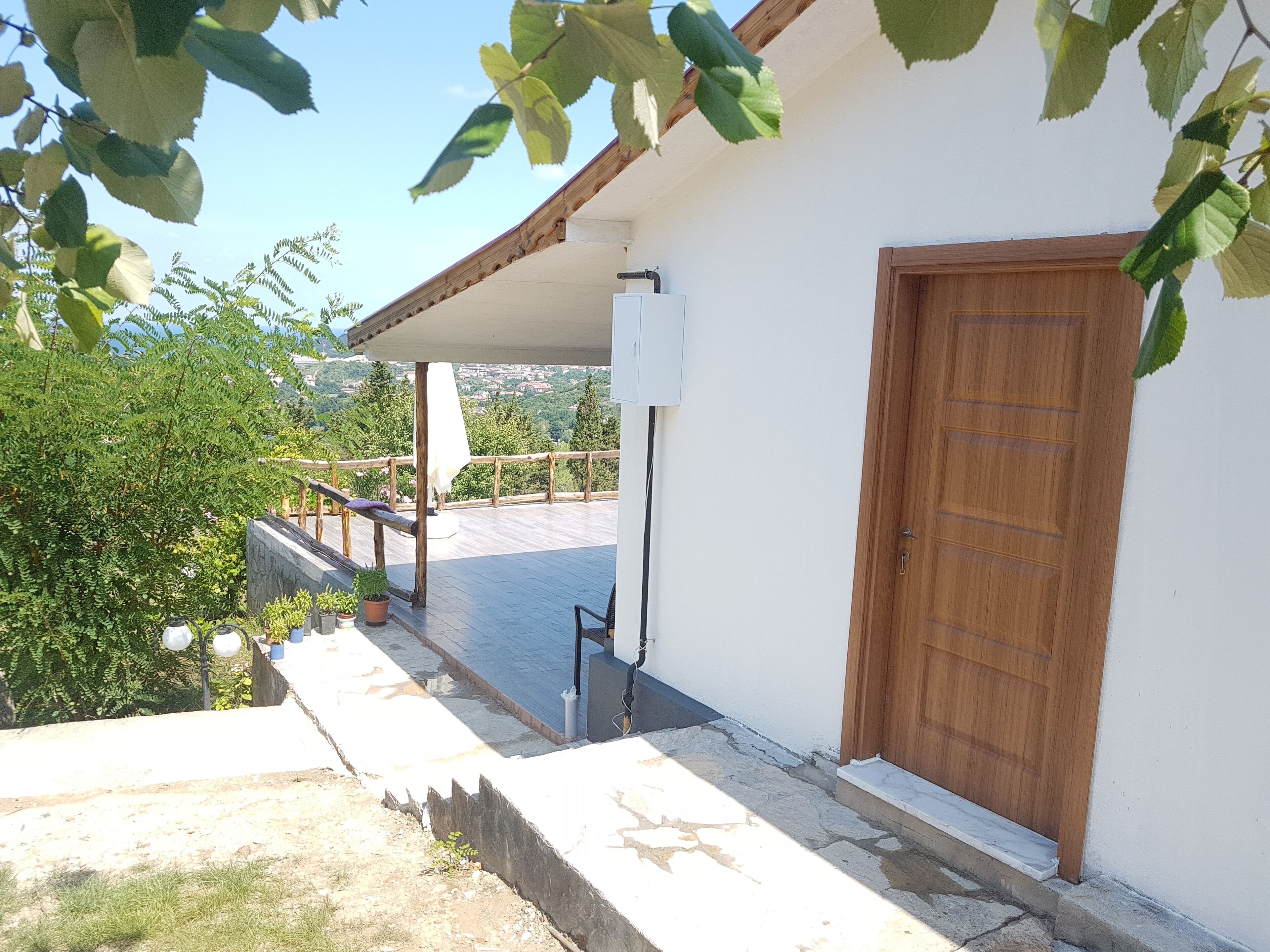 Un bâtiment doté d’une porte en bois, d’un mur blanc et d’un espace extérieur abrité avec une rambarde.