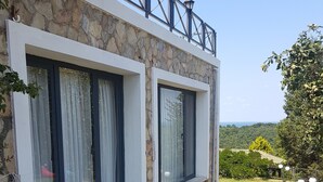 A stone building with two large windows, a stone pathway, and a view of a green landscape. - Ağva Stone House Boutique (Sile)