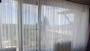 A room with sheer white curtains, a tiled floor, and a view of a garden and trees outside. - Ağva Stone House Boutique (Sile)