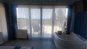 A room with a large sliding glass door, a jacuzzi tub, and a massage table with towels. - Ağva Stone House Boutique (Sile)