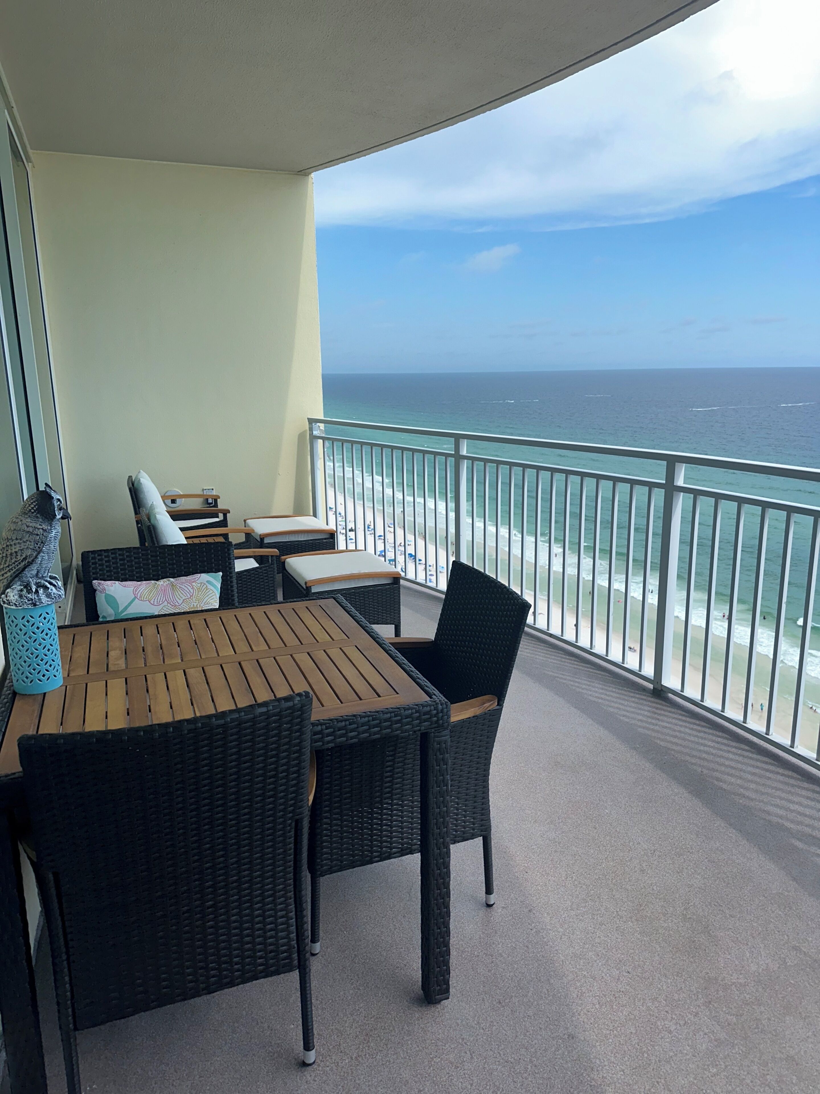 A balcony with a view of the ocean, furnished with wicker chairs and a table.