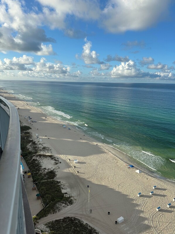 A beach with a clear view of the ocean and a pier in the distance.