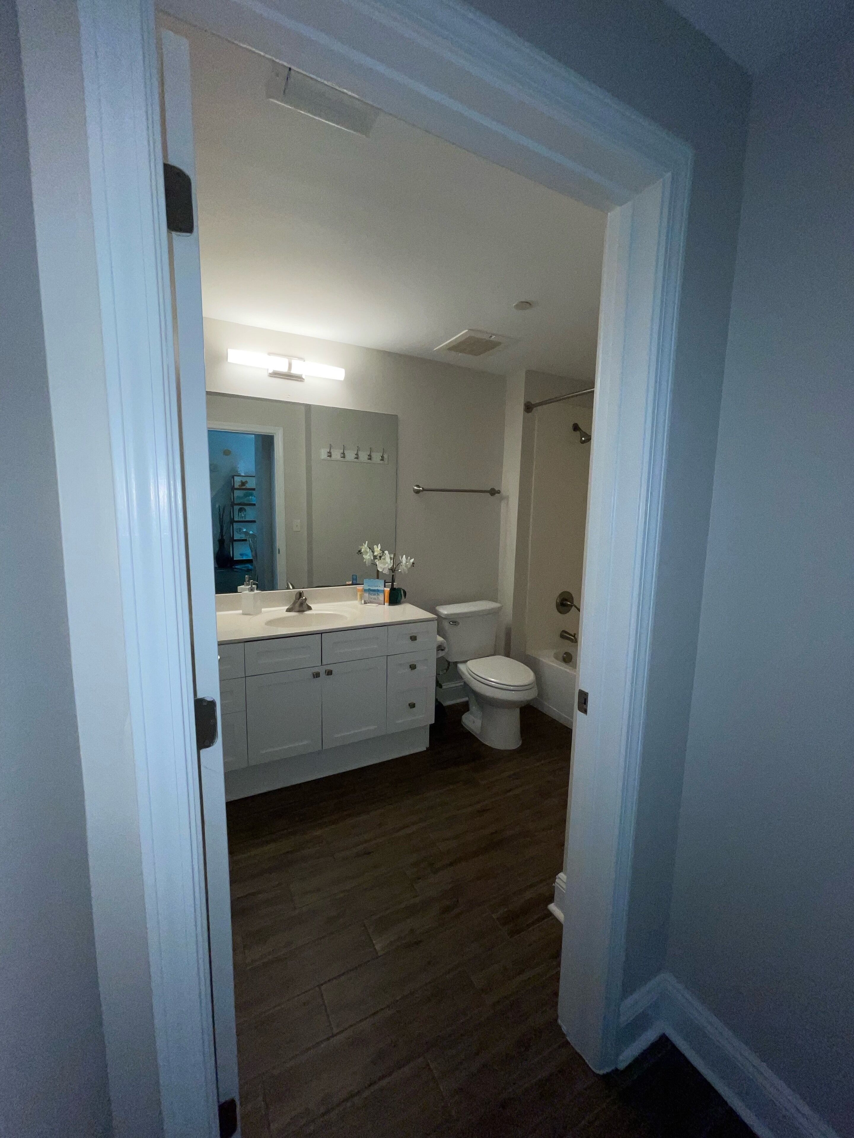 Un baño con lavamanos blanco, espejo e inodoro.