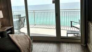 Et hotelværelse med en stor skydedør, der fører ud til en balkon med udsigt over havet.