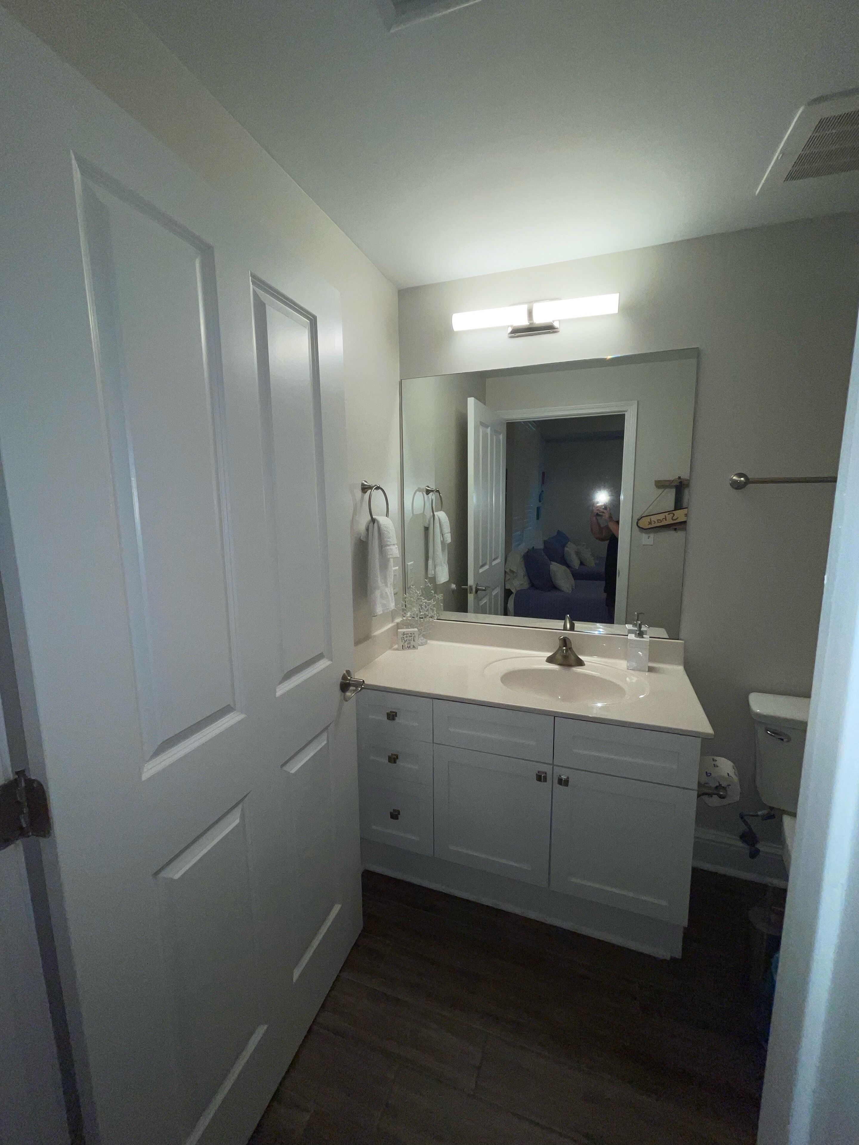 Un baño con lavamanos blanco, espejo y dos puertas.