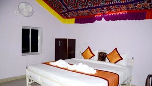A hotel room with a bed, a wardrobe, a window, and a ceiling fan. - Sam Desert Den (Jaisalmer)
