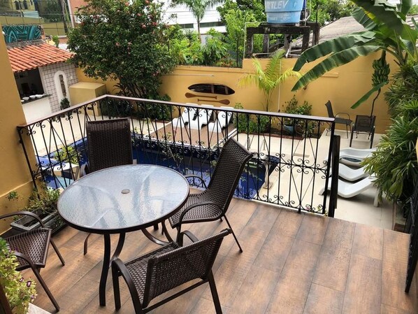 A balcony with a round table and four chairs, surrounded by a metal railing.