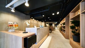 A modern reception area with a wooden counter, a reception desk, and a pathway leading to a seating area.