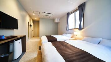A hotel room with two beds, a desk, a television, and a window with curtains.