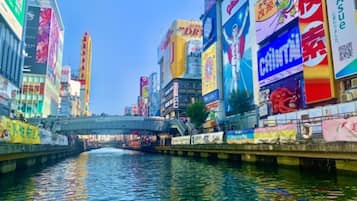 A busy urban street with a canal, surrounded by tall buildings with various advertisements.