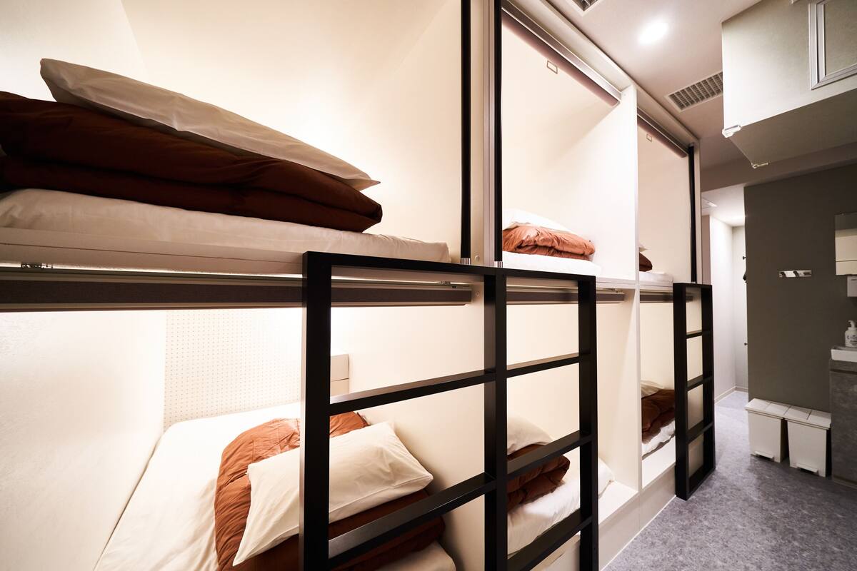 A bunk bed room with a wooden frame, a small desk, and a bench.
