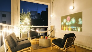 A balcony with two wicker chairs, a round table, and a hammock.